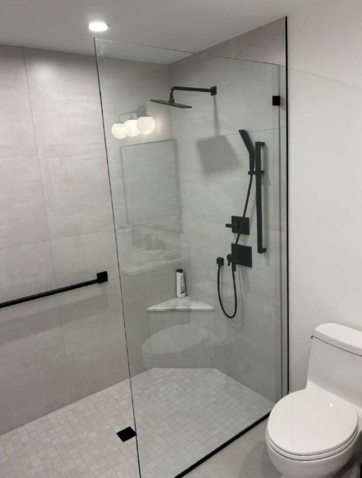 Modern bathroom with a glass shower enclosure, black fixtures, and a white toilet.