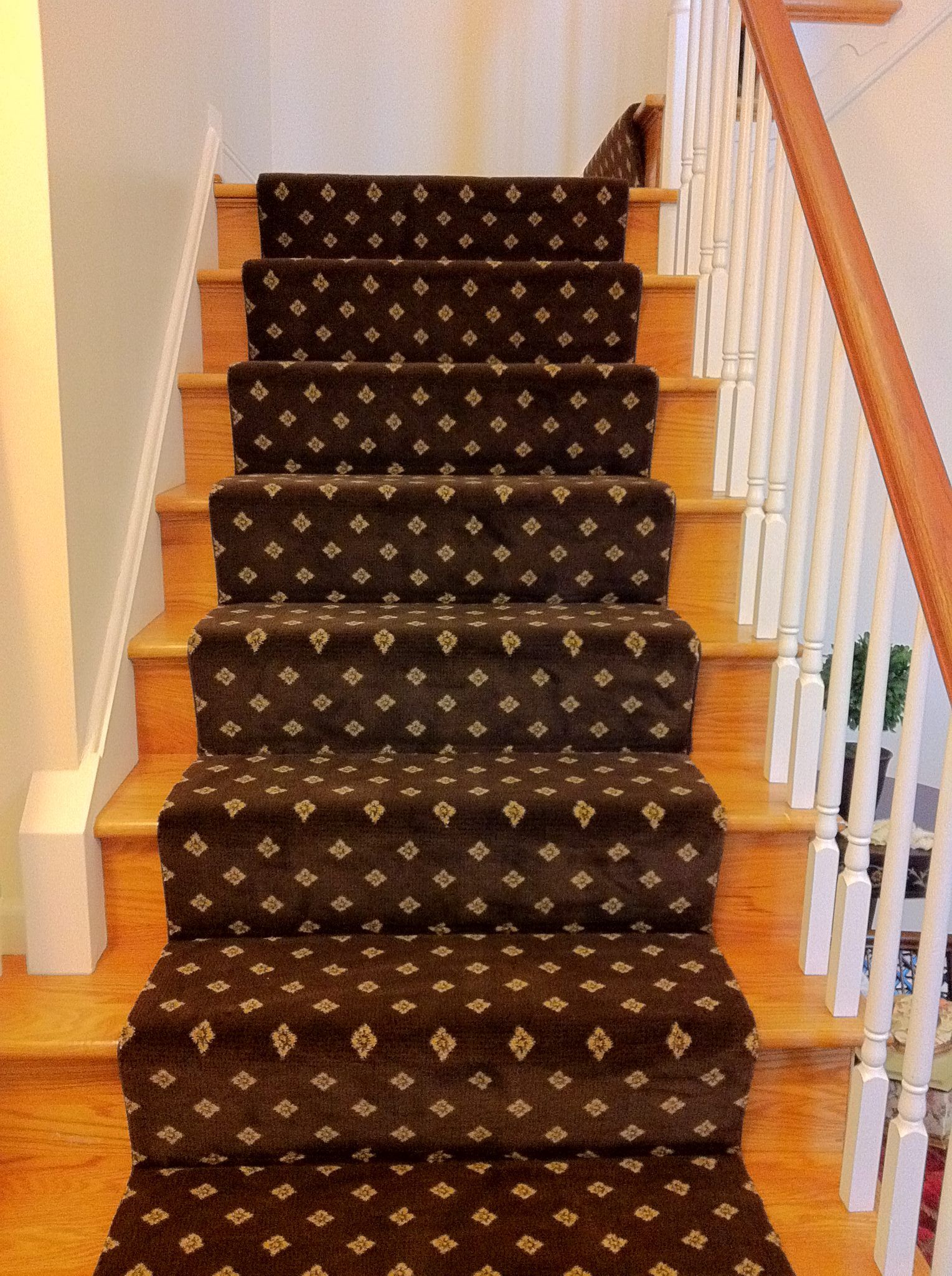 A staircase with a brown carpet and a white railing