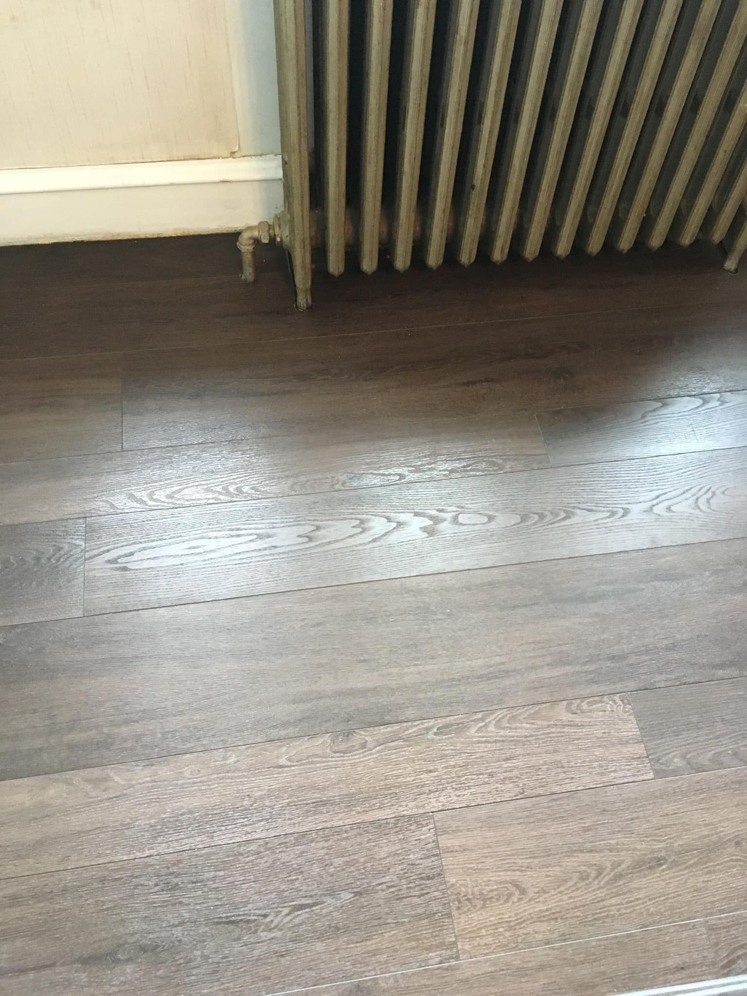 A wooden floor next to a radiator in a room.