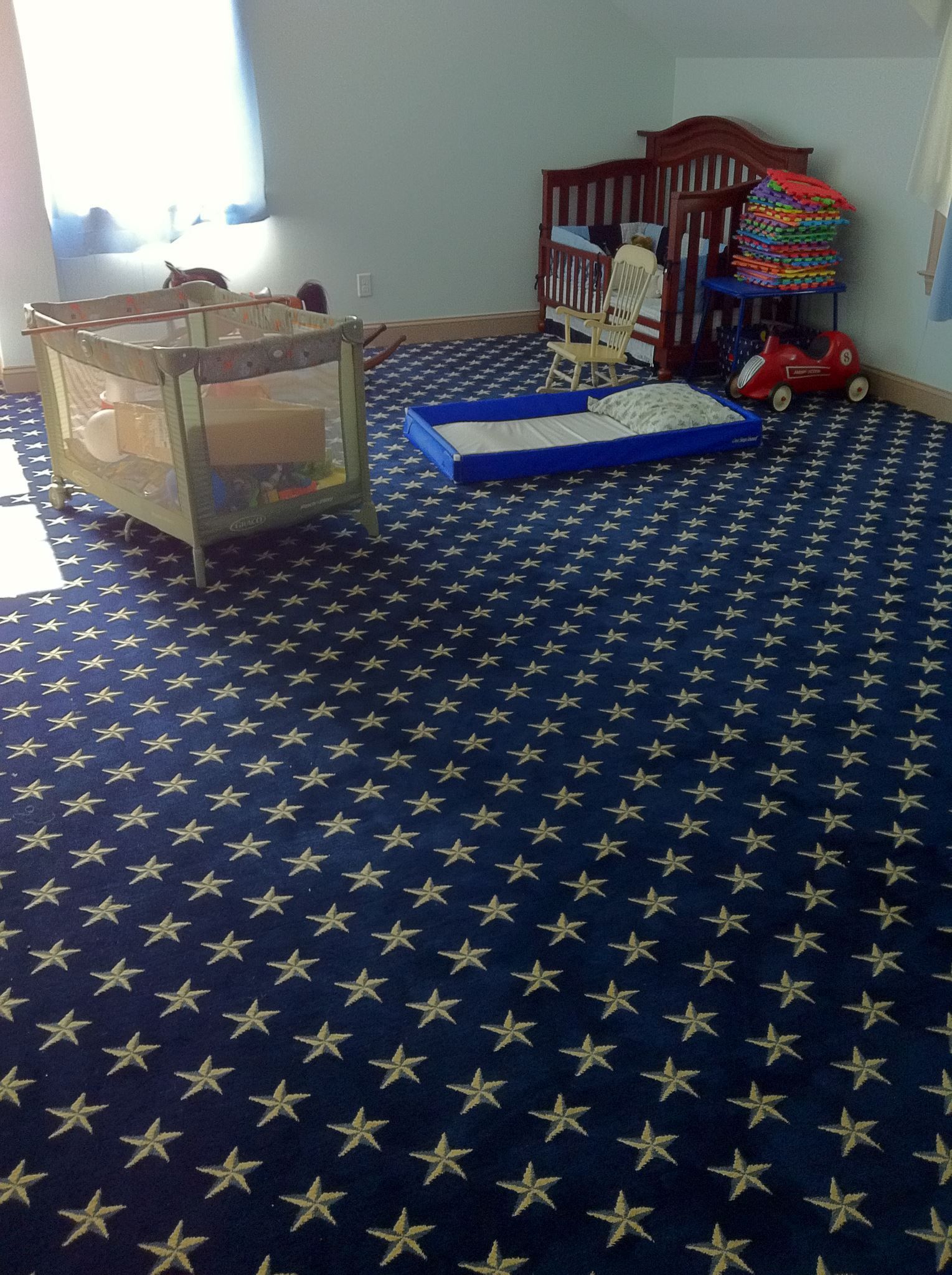 A blue carpet with white stars on it in a nursery