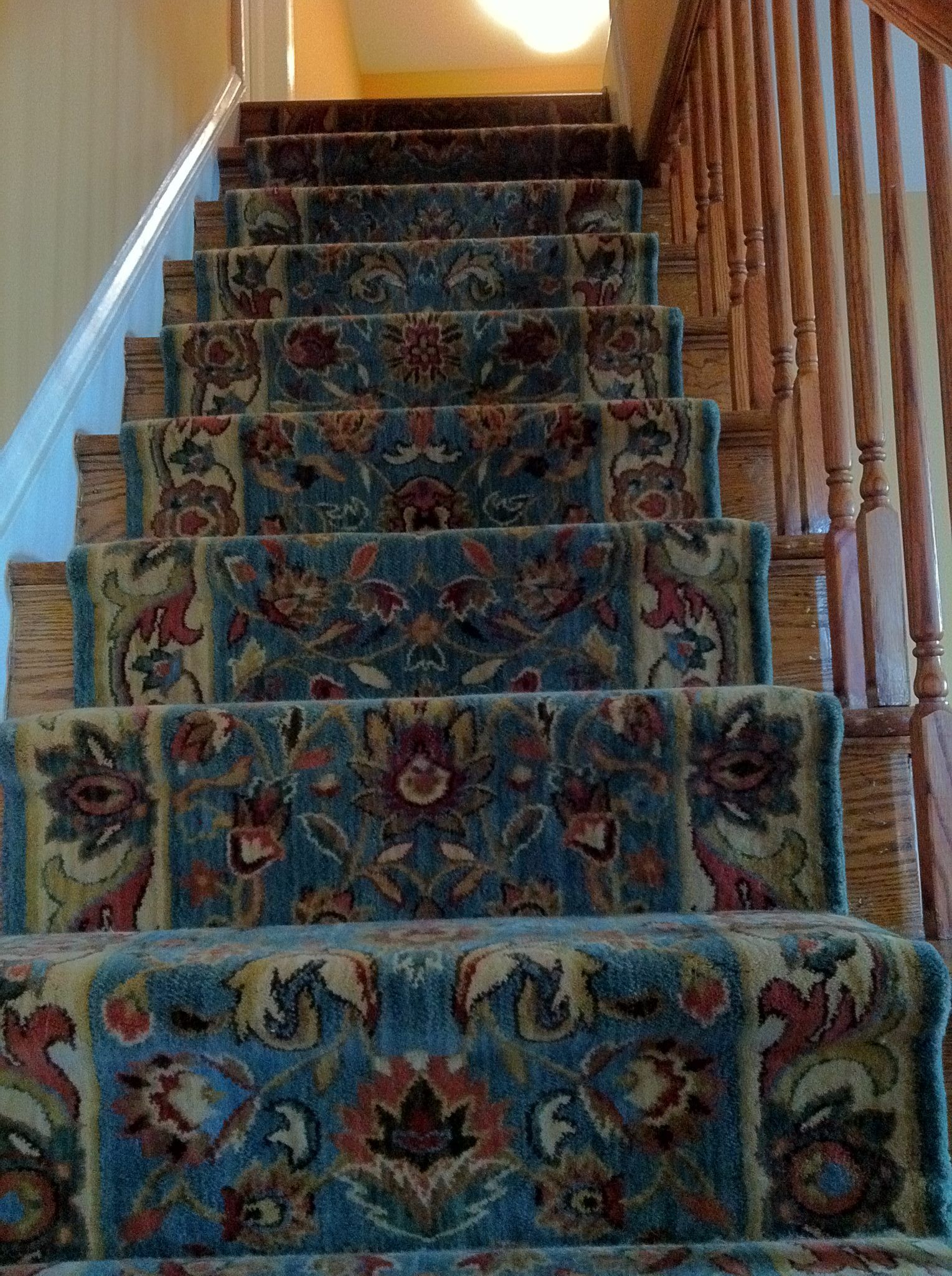 A staircase with a floral carpet on it and a wooden railing.