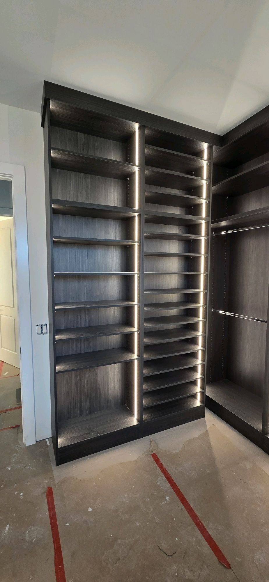 Open black pantry cabinets with empty shelves in a room under construction