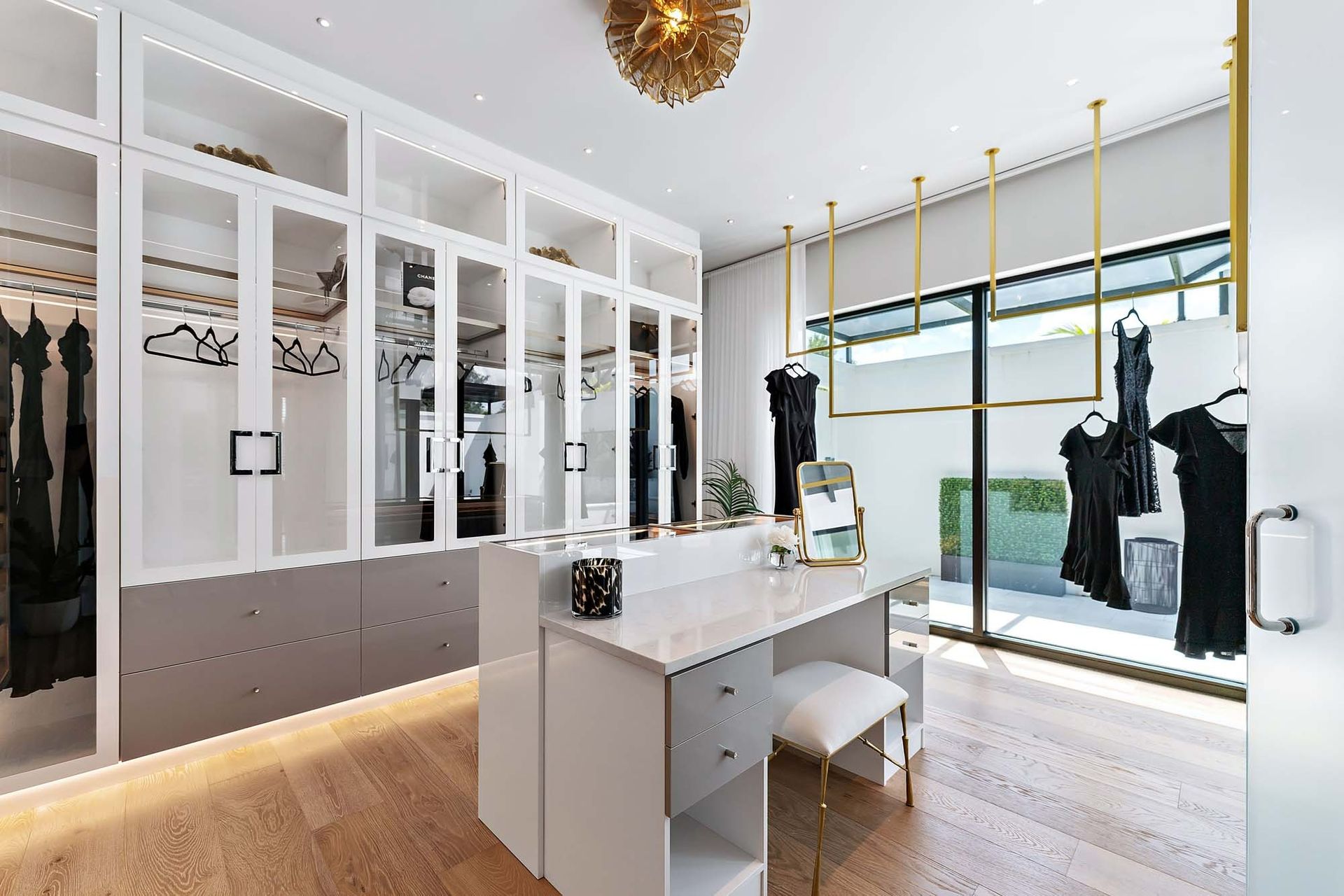 Modern boutique dressing room with white cabinetry, vanity, and hanging clothes in a bright, minimalist space