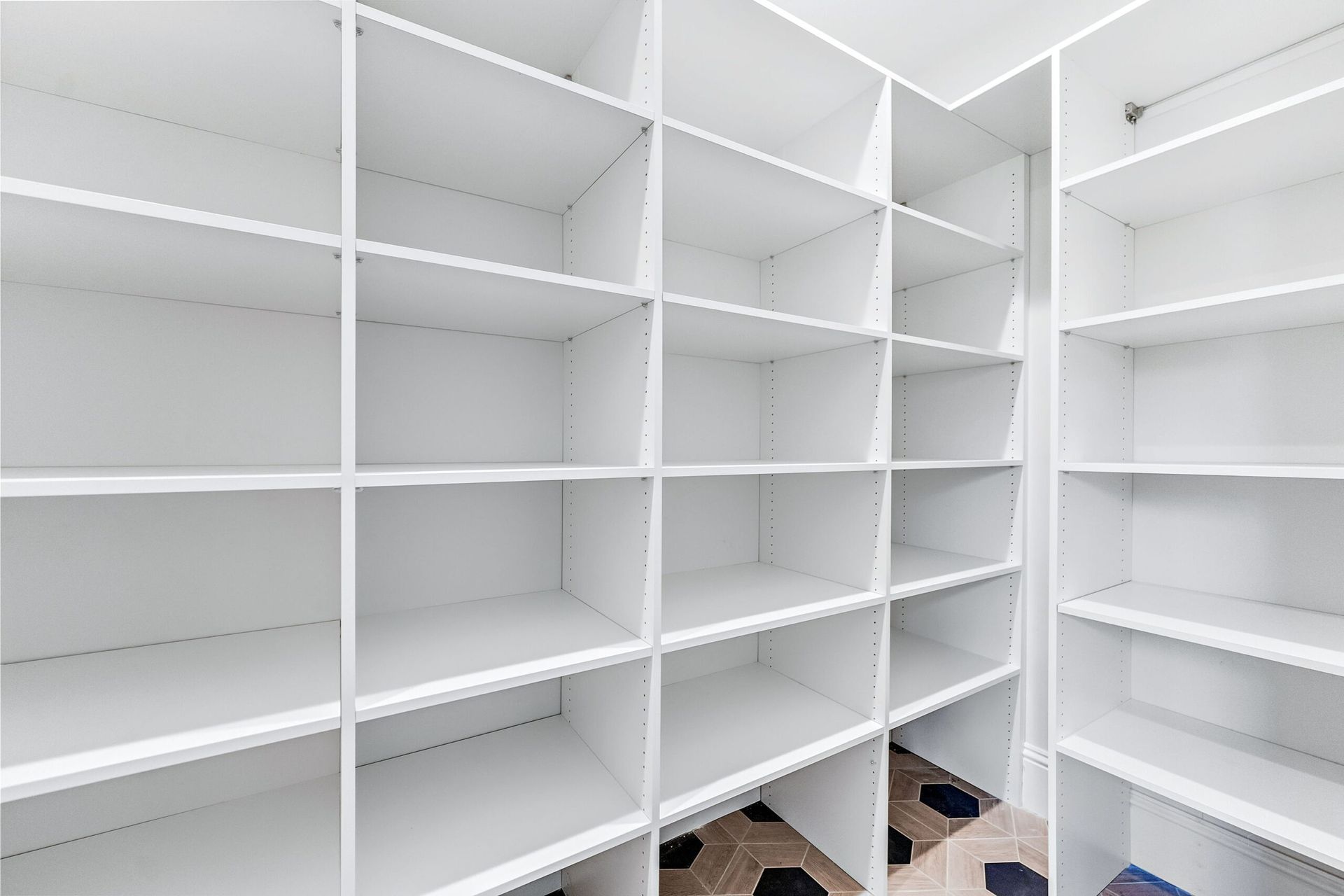 White built-in empty shelving in a bright walk-in closet or pantry room