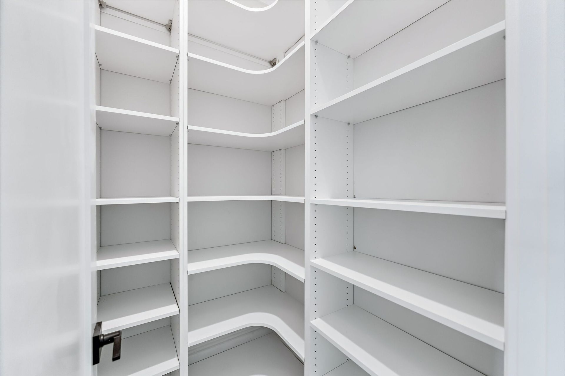 Empty white walk-in closet with built-in shelves and hanging rods