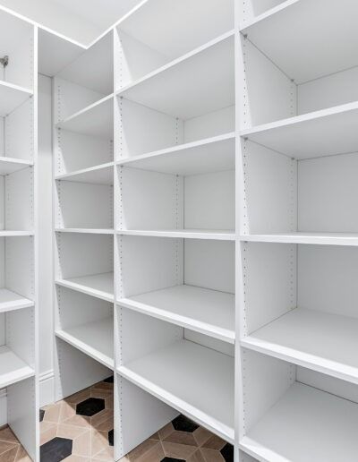 White built-in shelving units in an empty walk-in closet area.