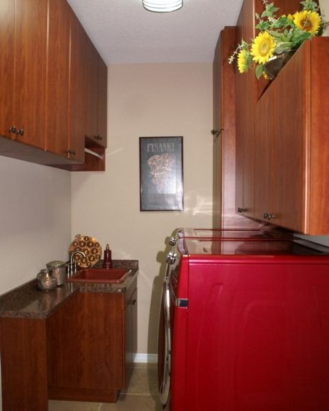 Narrow kitchen with wood cabinets, red appliance, and sunflowers on top of the cabinet.