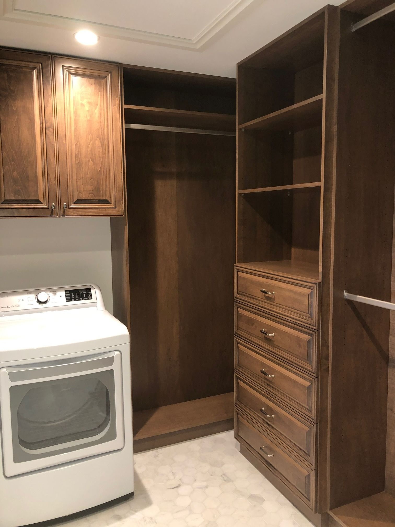 Laundry room with a white washer, wood cabinets, and a built-in closet with drawers and shelves