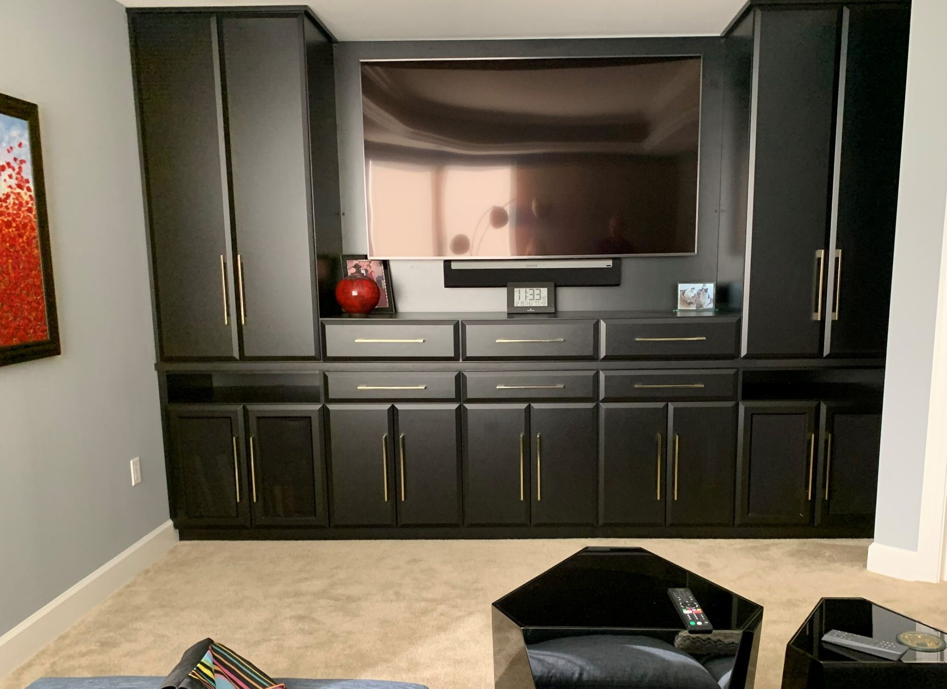 Black built-in media cabinet with TV recess, drawers, and cabinets in a beige room