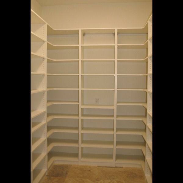 Empty white walk-in closet with built-in shelves and hanging rods