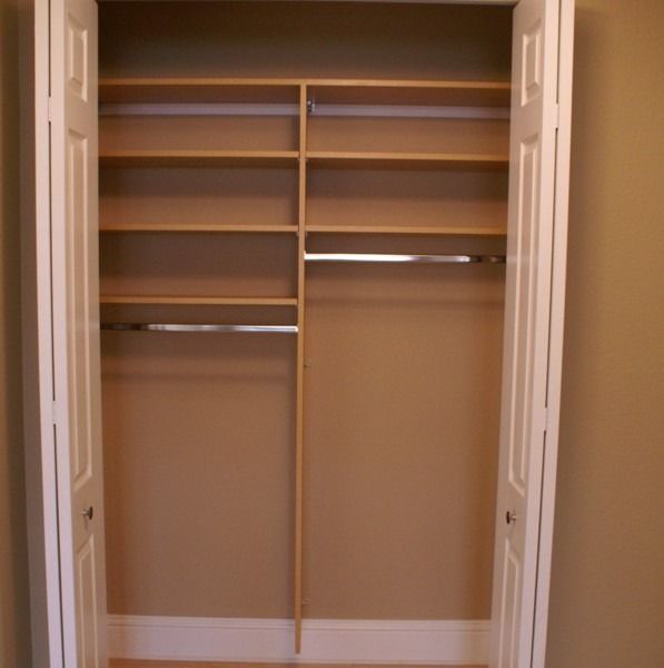 Open closet with empty shelves and hanging rods on beige walls.