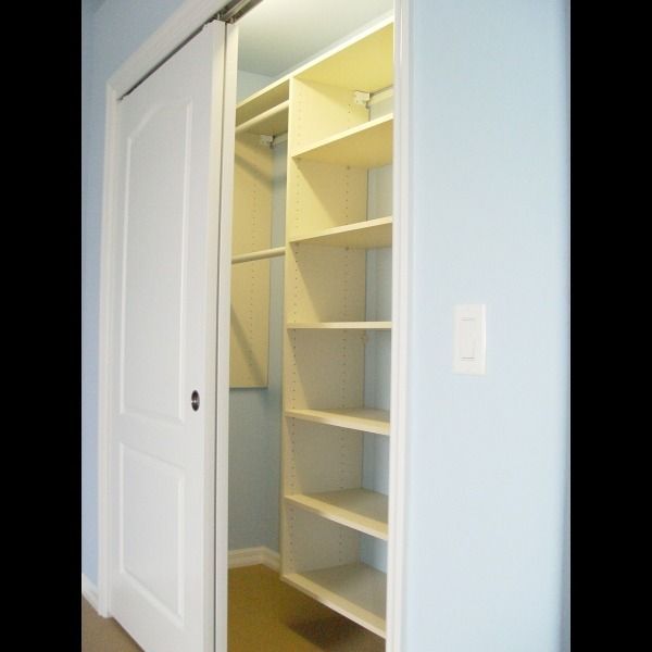 Open closet with white sliding doors and built-in shelves in a light blue room