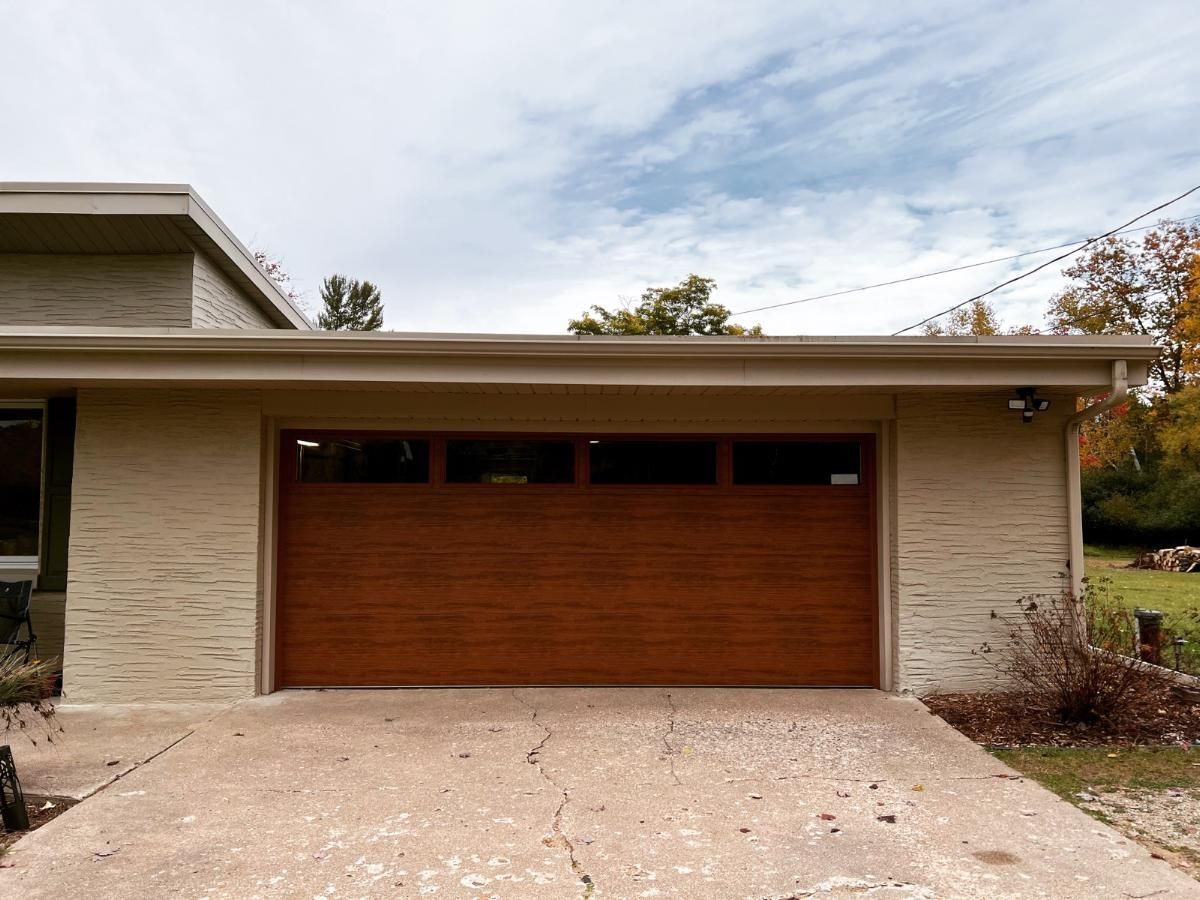 A white brick house with a wooden garage door