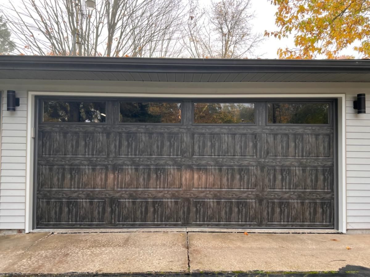 A large garage door with a lot of windows is sitting on the side of a house.