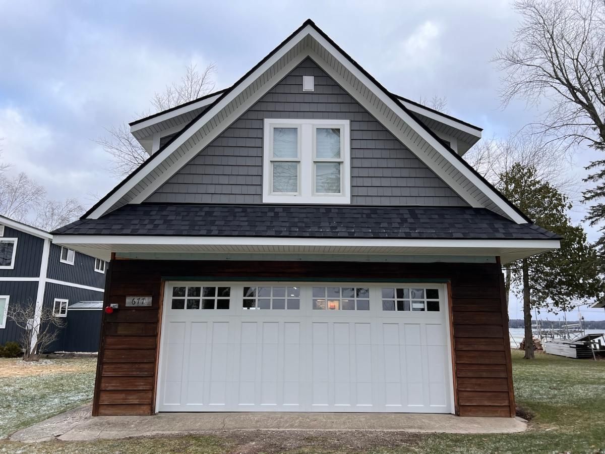 A small house with a garage and a window on the top of it.