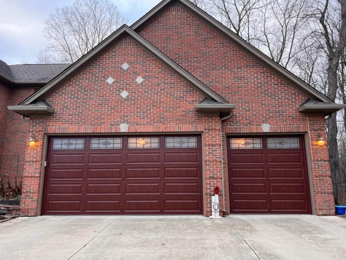 A brick house with two red garage doors and a fire hydrant in front of it.