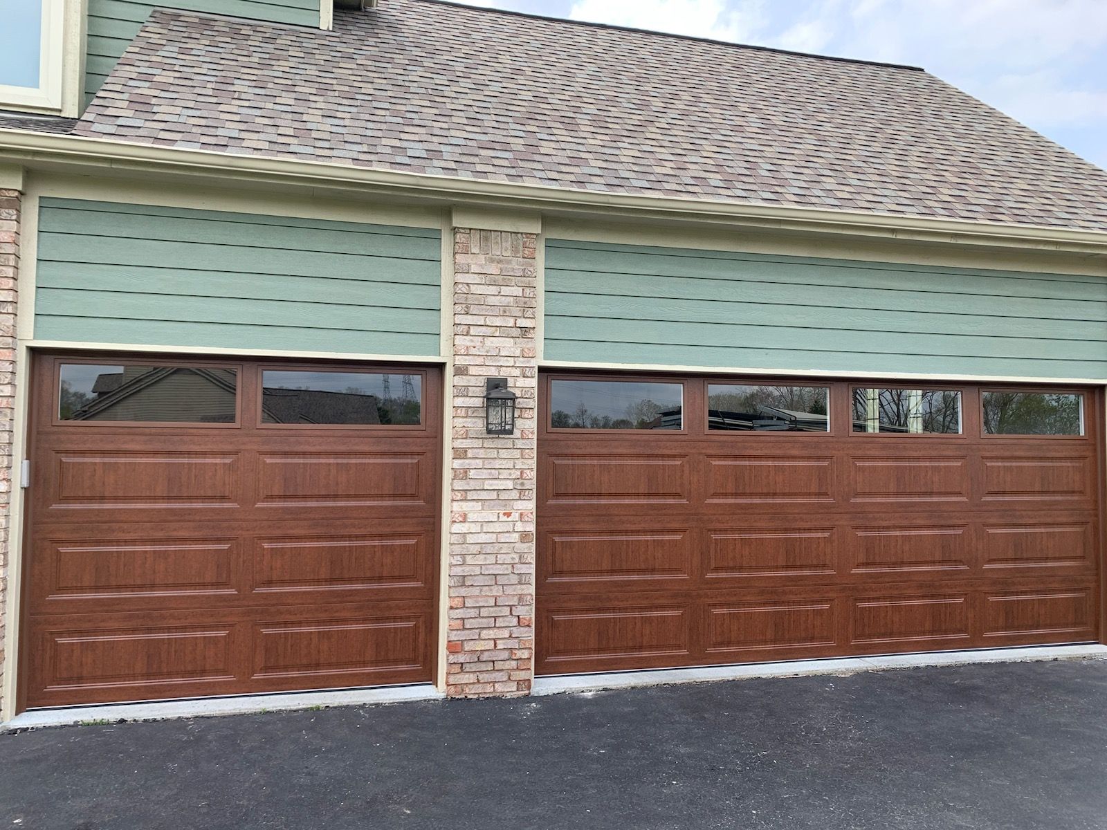 There are two garage doors on the side of a house.