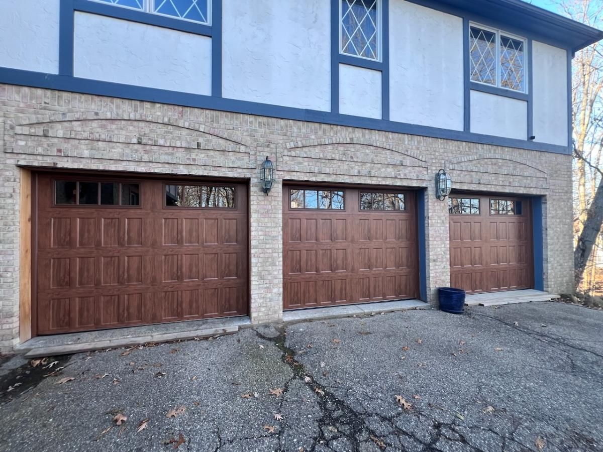 There are three garage doors on the side of a house.