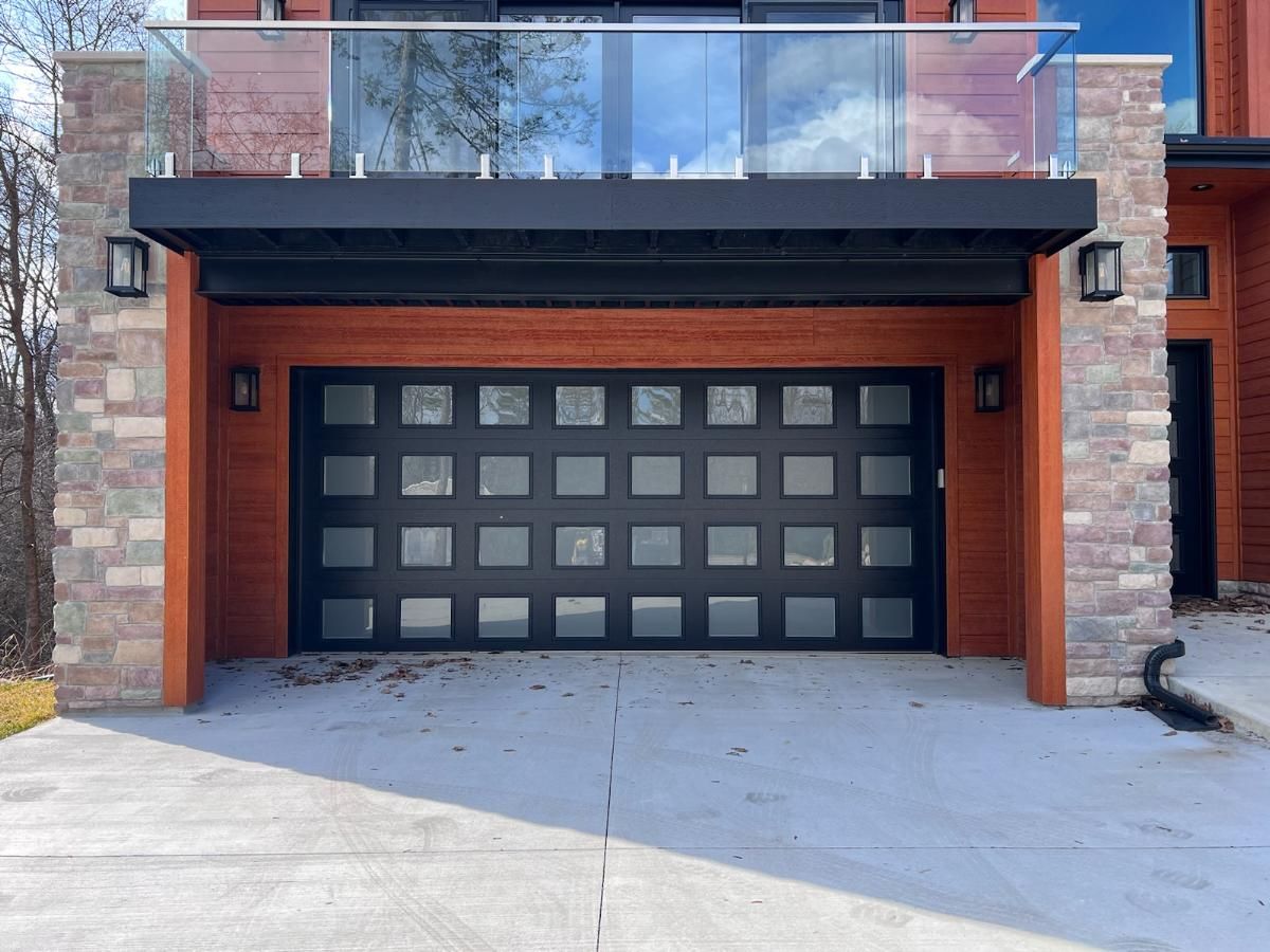 A black garage door is sitting in front of a brick house.