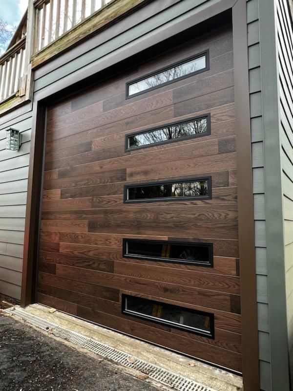 A wooden garage door with three windows on the side of a house.