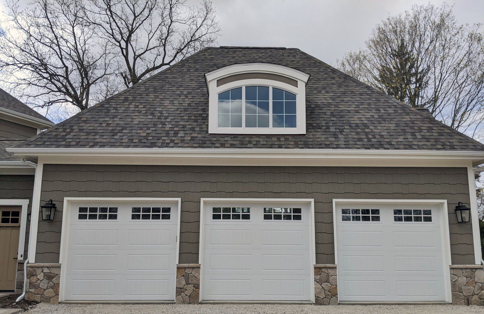 A house with three garage doors and a window on the roof.