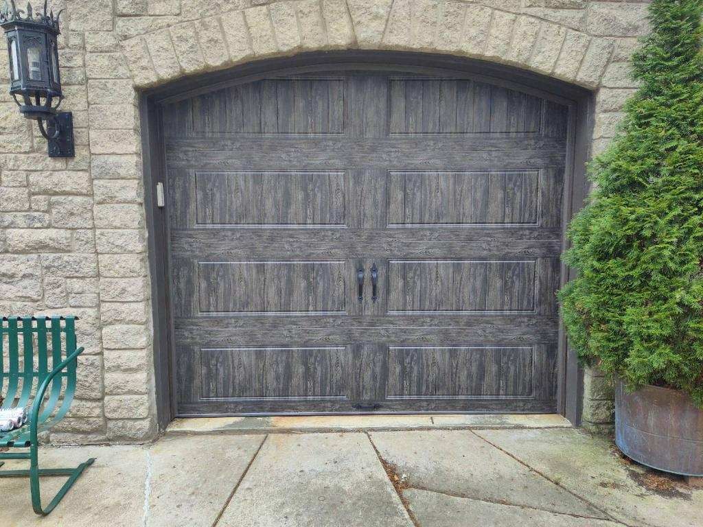A black garage door is sitting in front of a brick building.