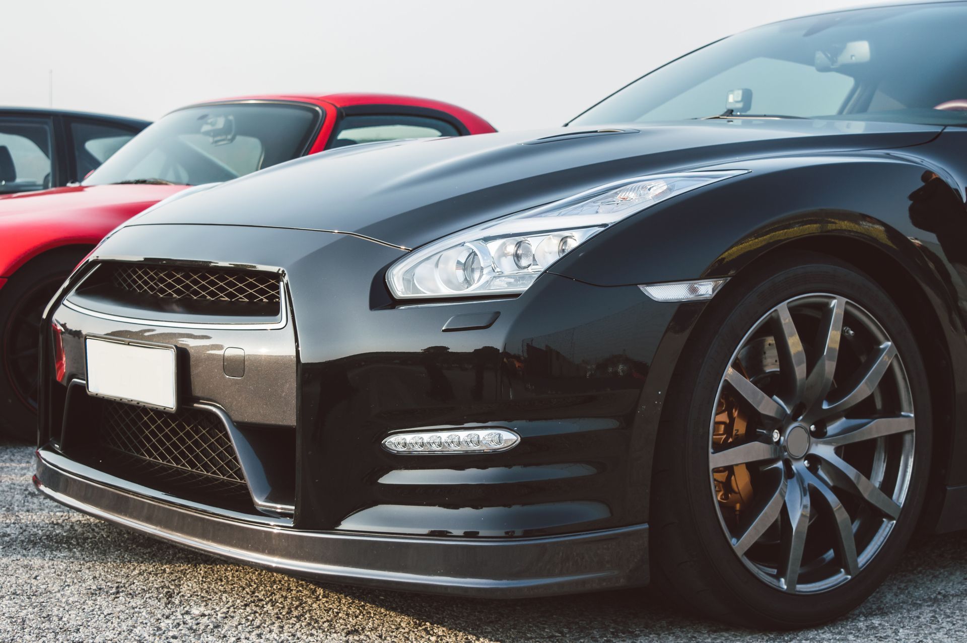 A black sports car is parked next to a red sports car.