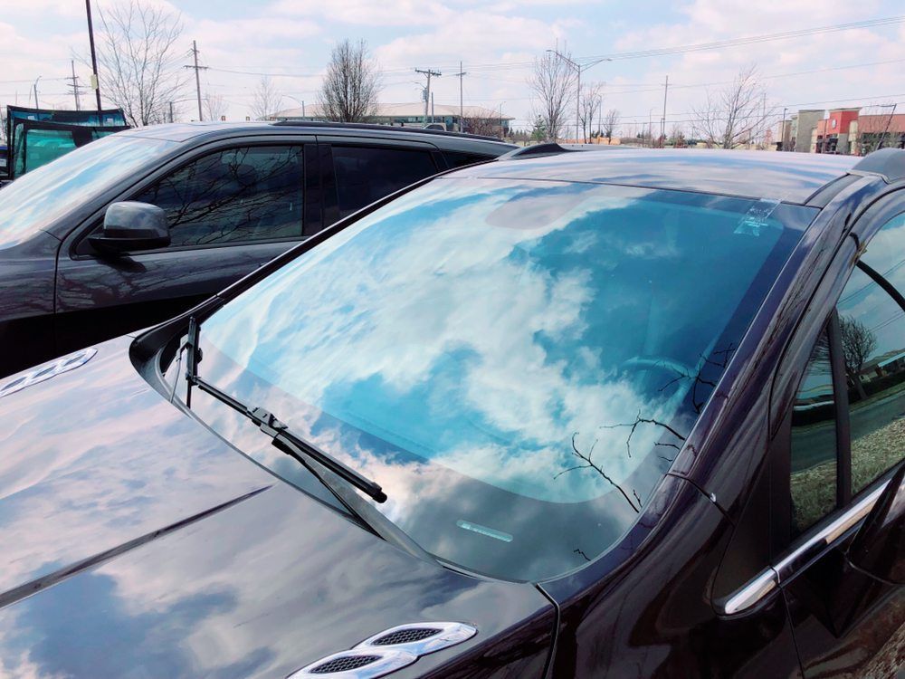Two black cars are parked next to each other in a parking lot.