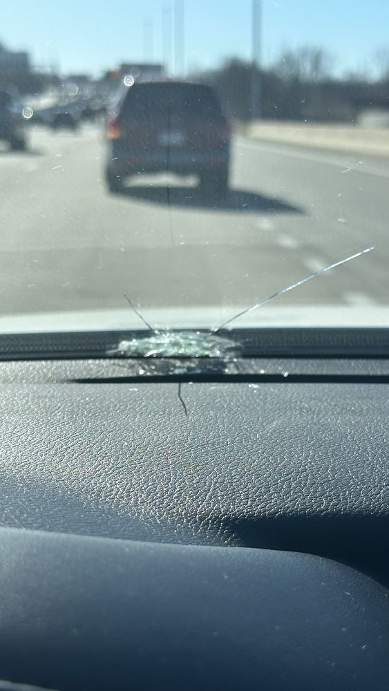 A car with a cracked windshield is driving down a highway.