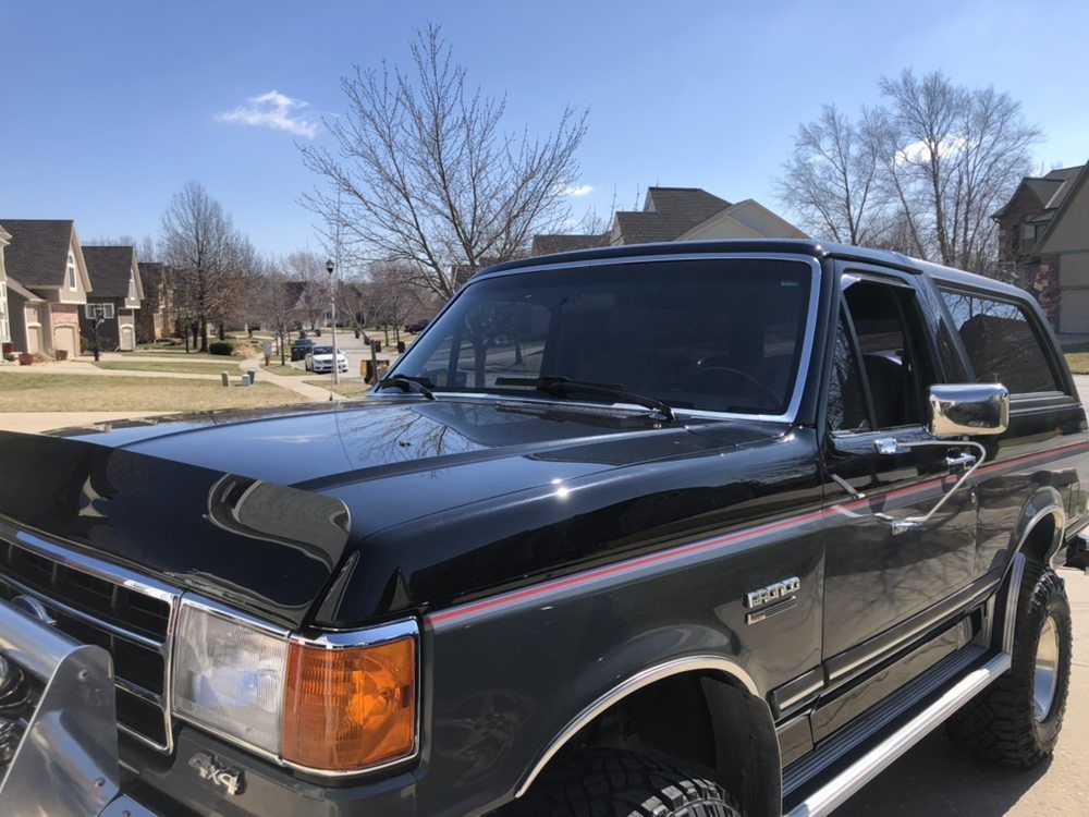 A black ford bronco is parked in a driveway in a residential area.