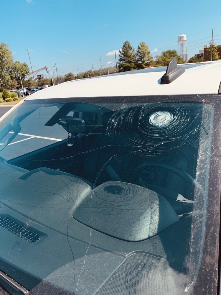 A car with a broken windshield is parked in a parking lot.