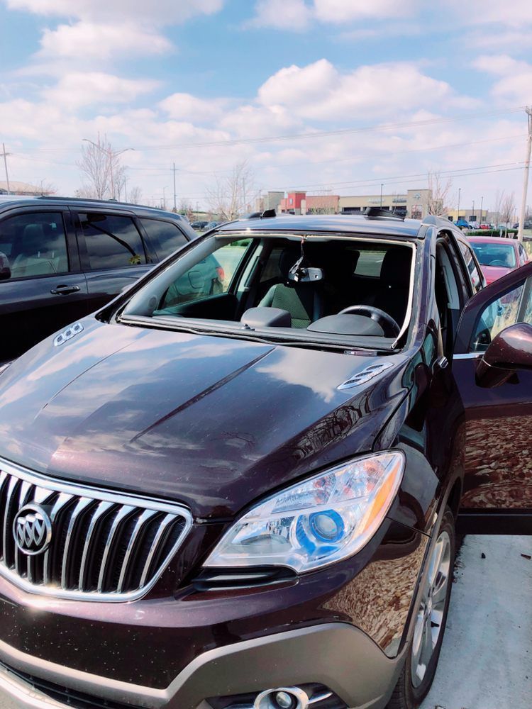A purple buick parked in a parking lot with its door open.