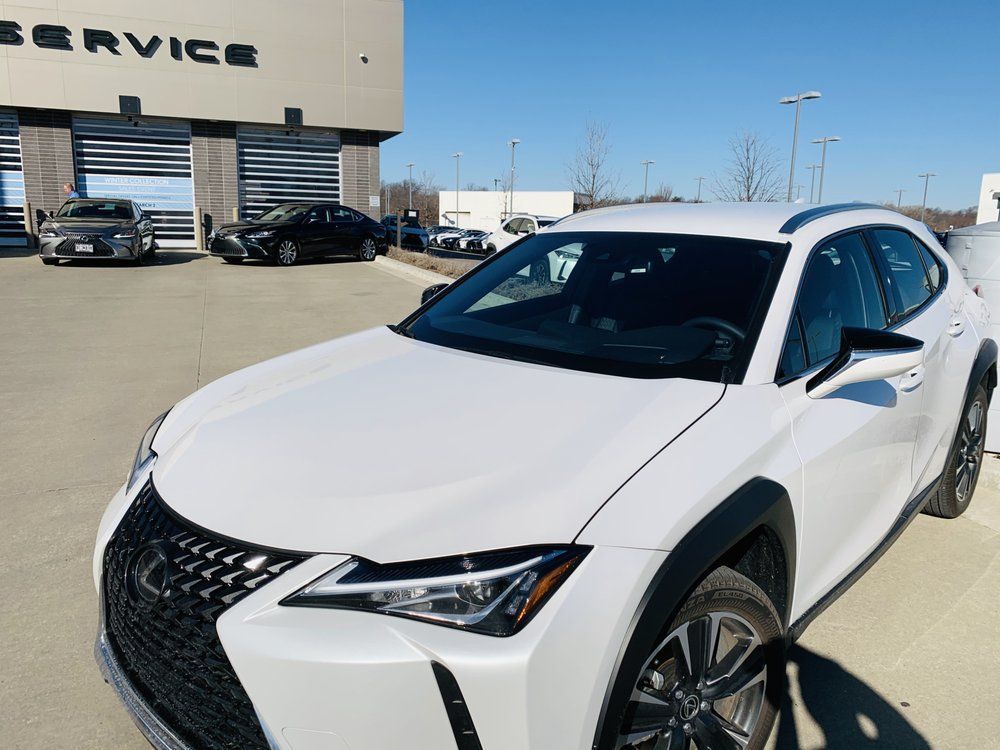 A white lexus is parked in front of a service building