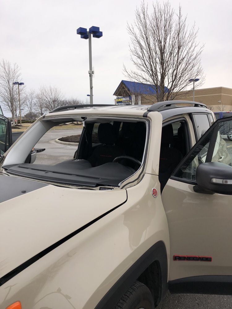 A jeep renegade with a broken windshield is parked in a parking lot.