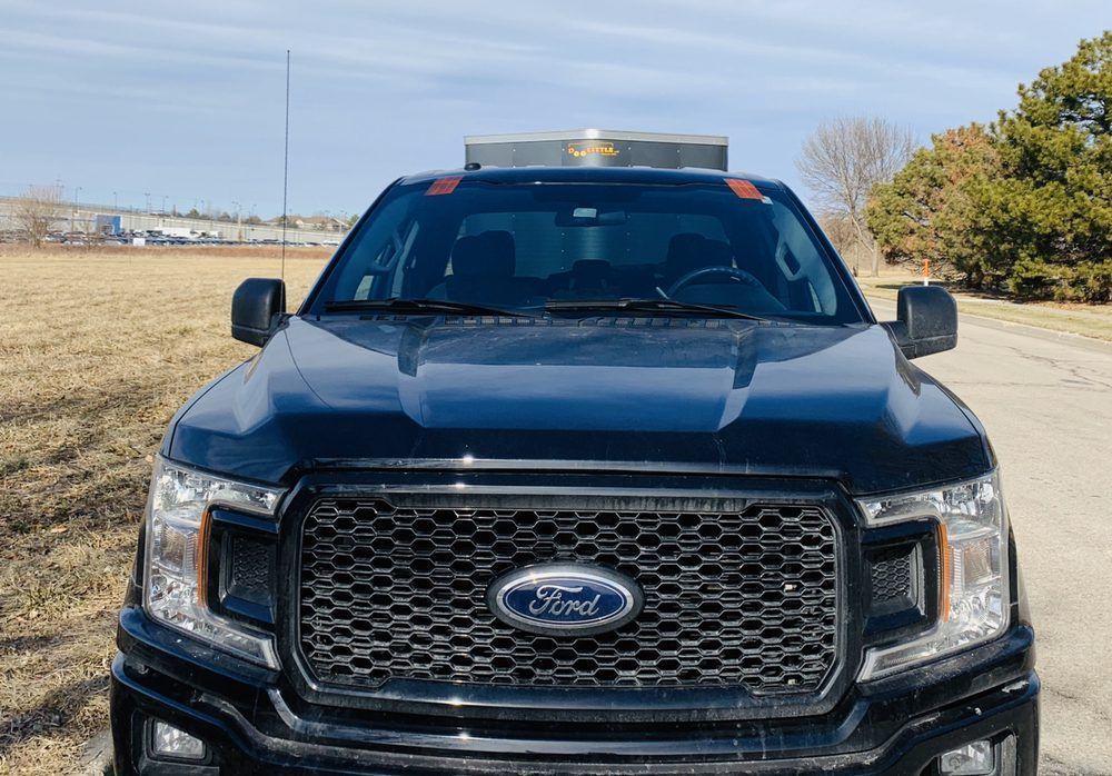 A black ford truck is parked on the side of a road.