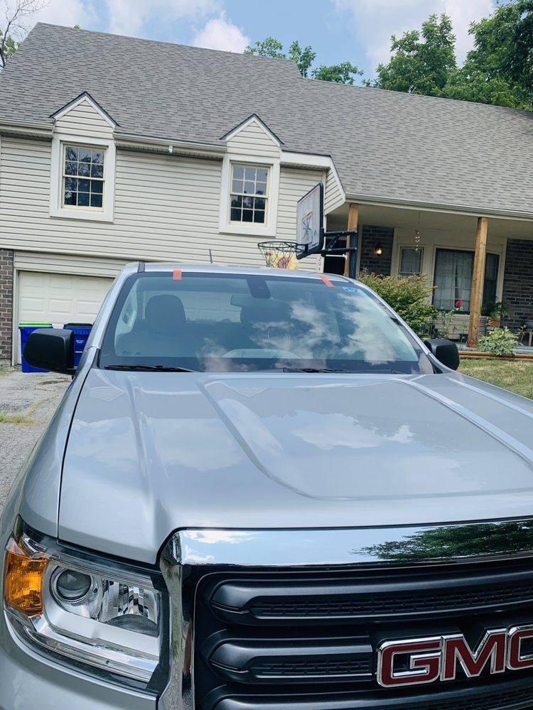 A silver gmc truck is parked in front of a house.