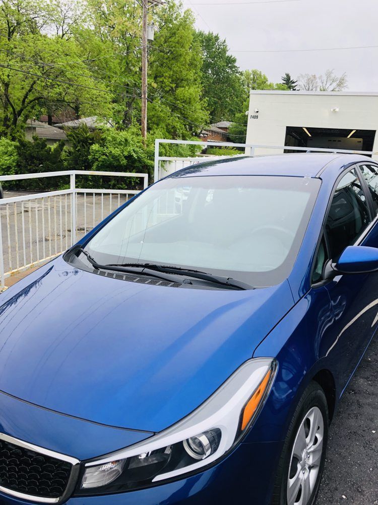 A blue car is parked in a parking lot in front of a building.