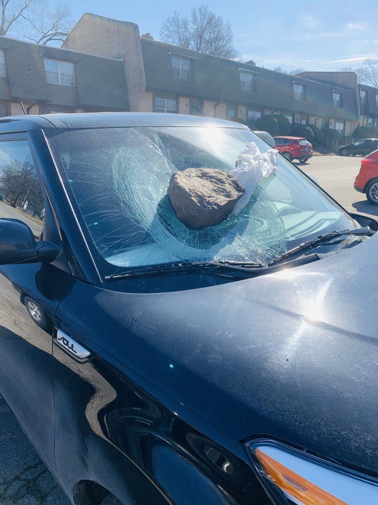 A large rock is sitting on the windshield of a car.