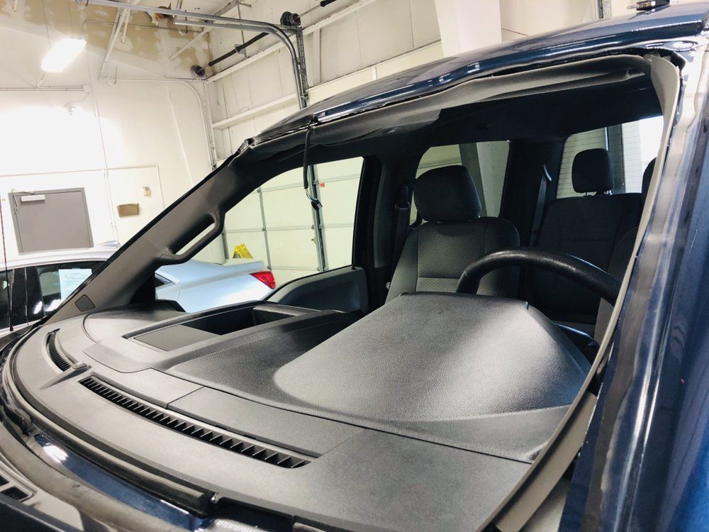 A car with a broken windshield is in a garage