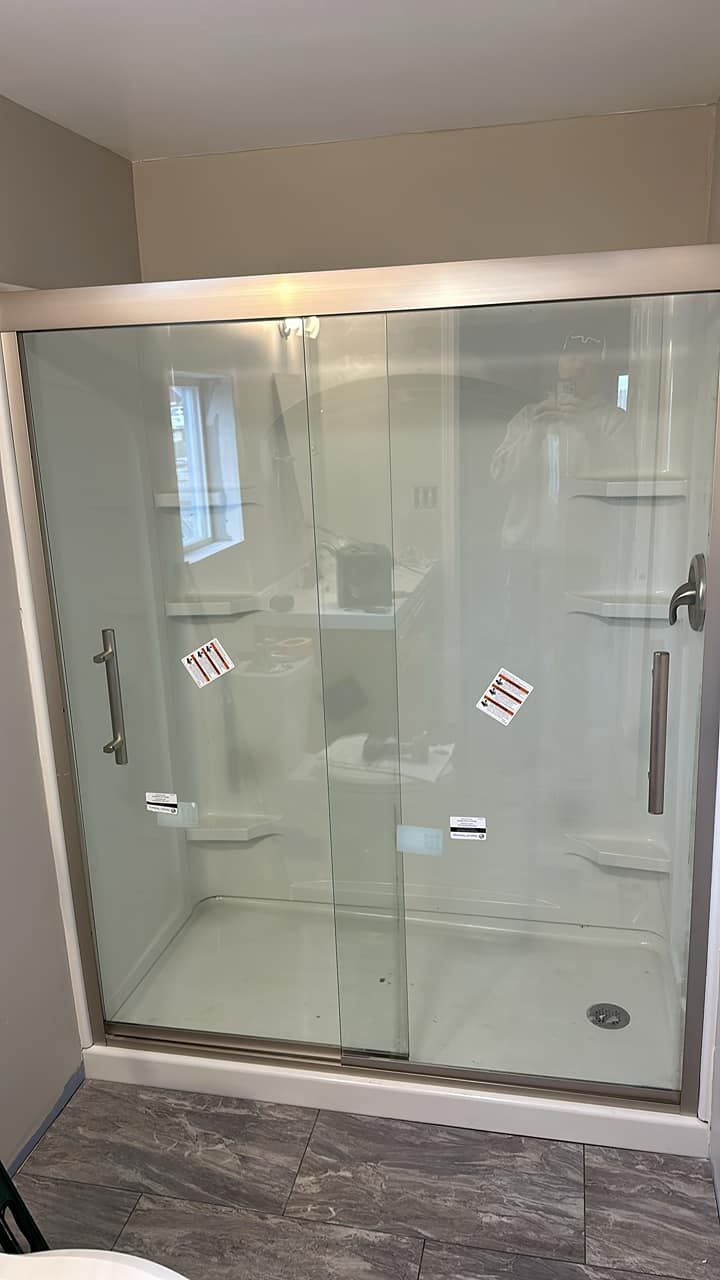 Glass walk-in shower with chrome fixtures and gray tile floor in a bathroom