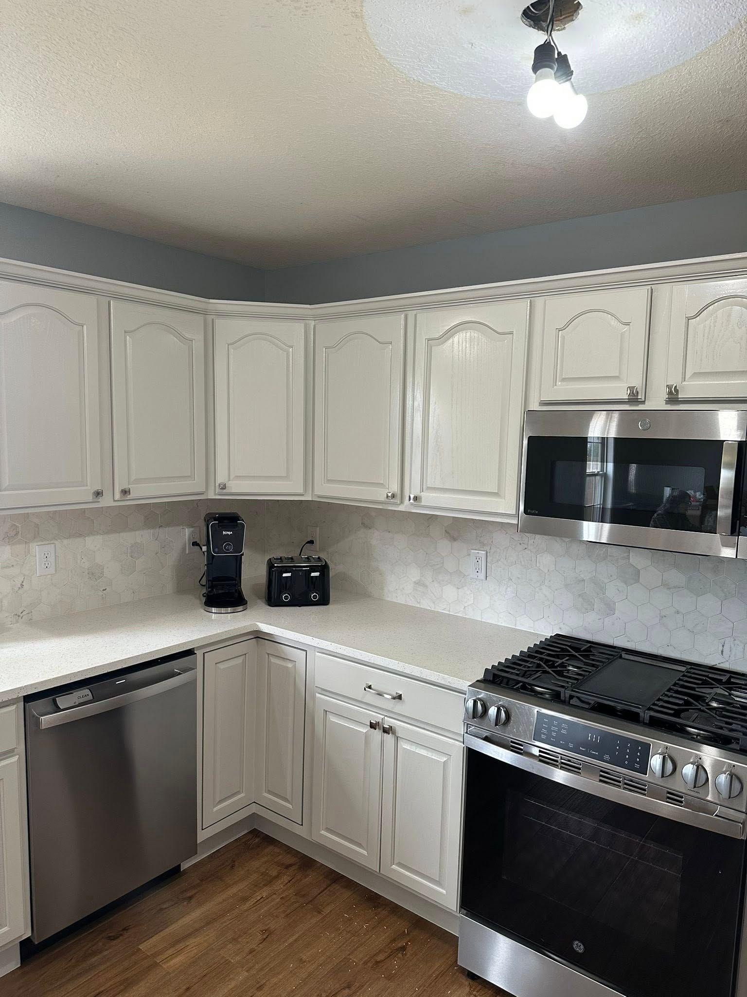 Bright kitchen with white cabinets, stainless steel appliances, and a speckled countertop