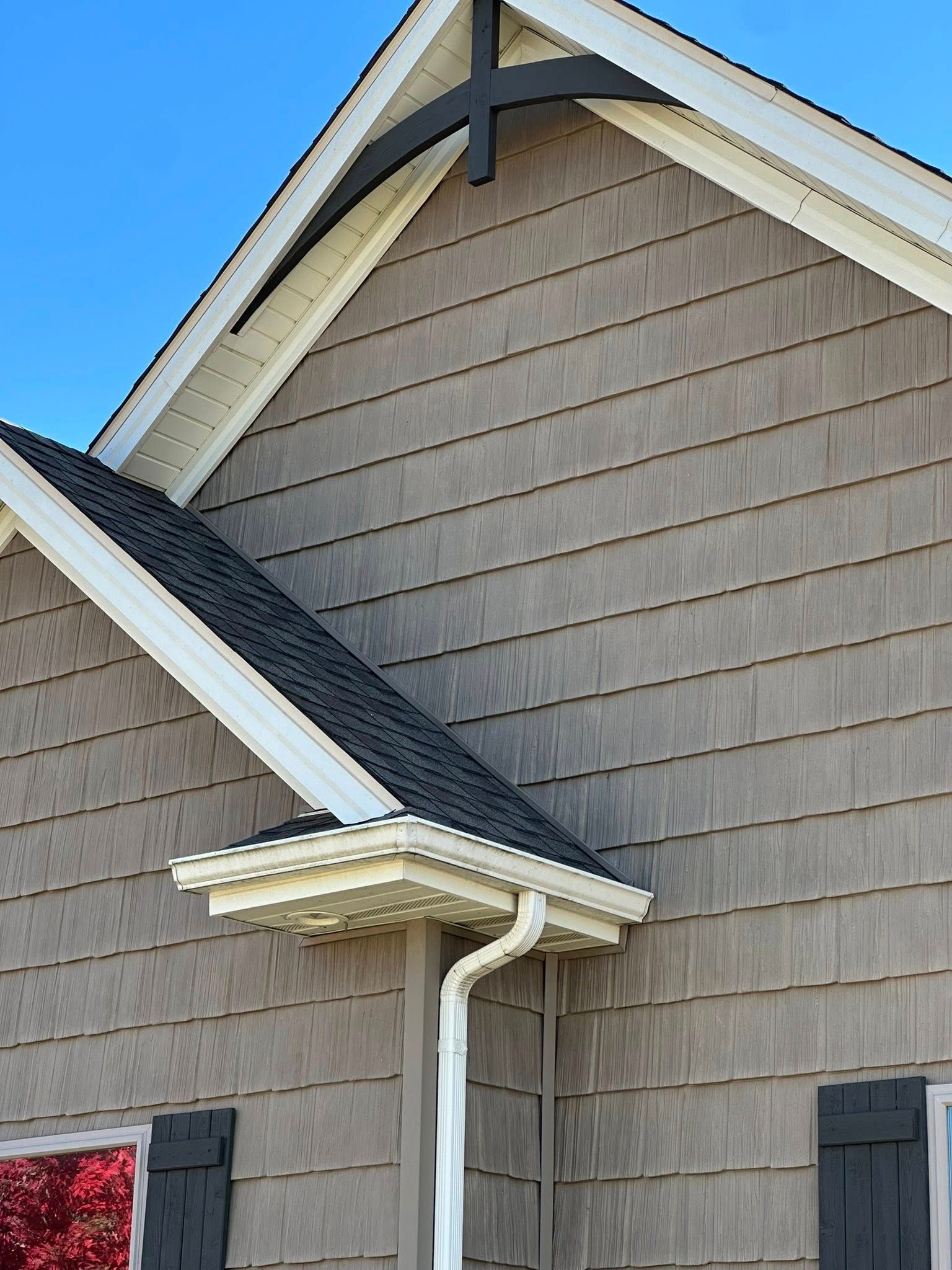 House exterior with gray shingle siding, white trim, dark shutters, and a blue sky background
