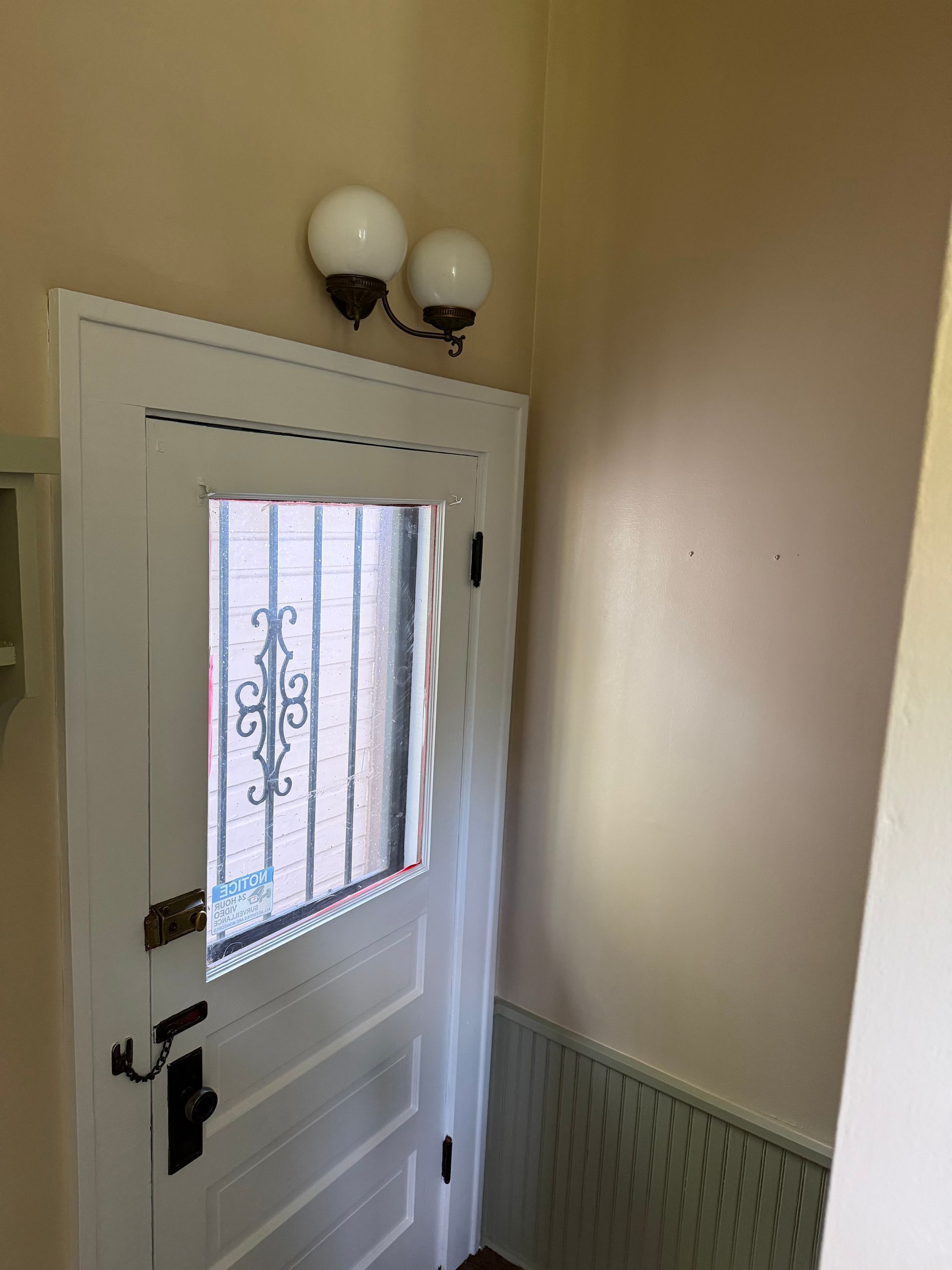 Interior entryway with a white front door, window, and wall-mounted light fixture.