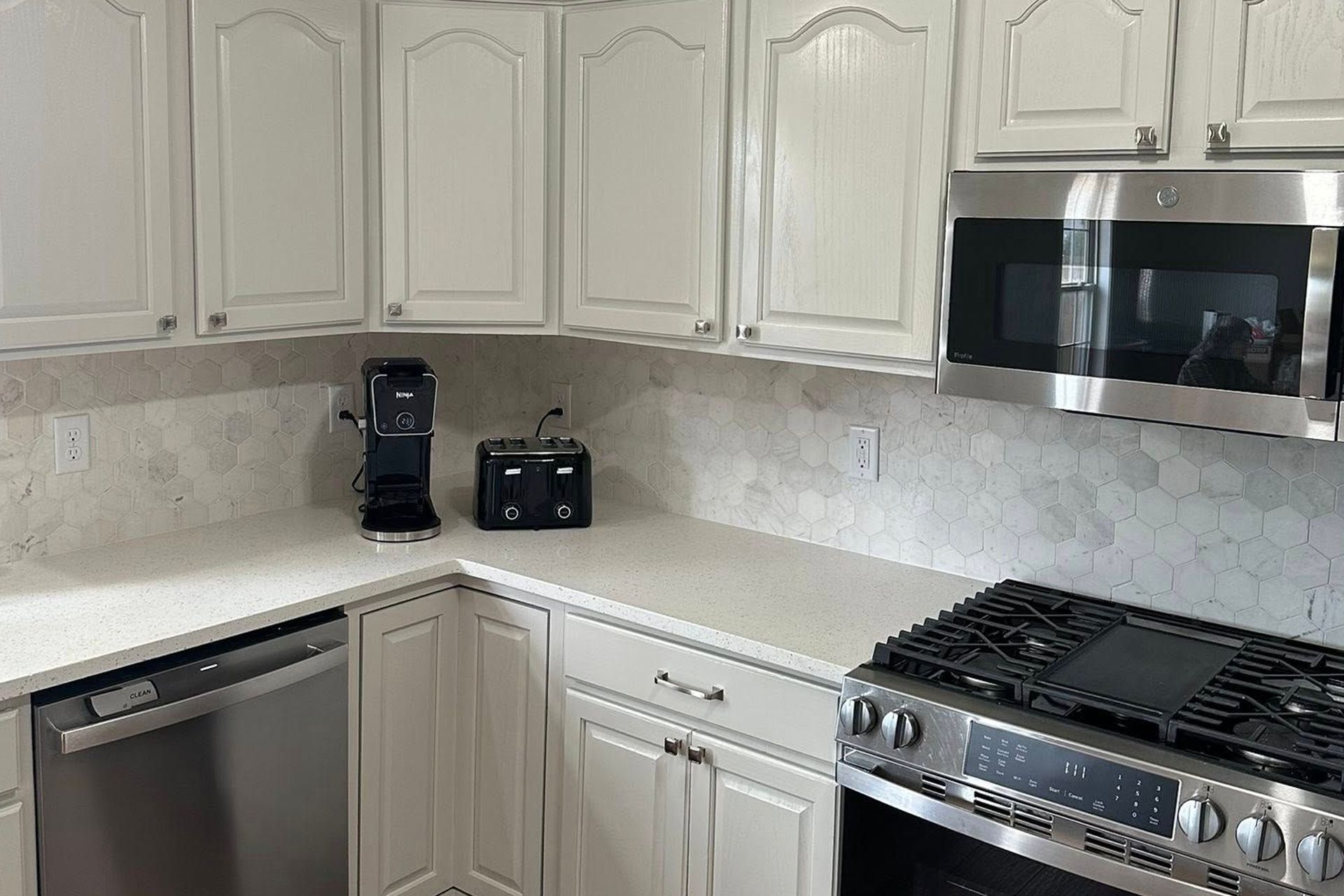 Bright kitchen with cream cabinets, granite countertop, stainless steel appliances, and coffee maker on the counter.