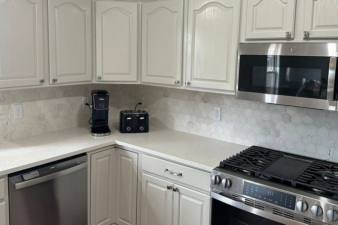 Bright kitchen with cream cabinets, granite countertop, stainless steel appliances, and coffee maker on the counter.