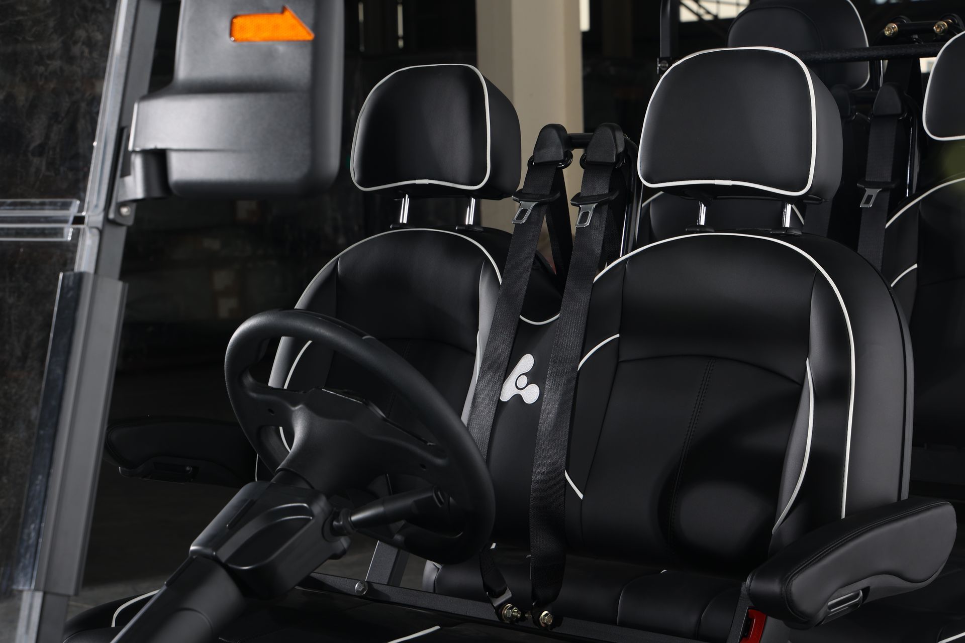 The inside of a golf cart with black seats and a steering wheel