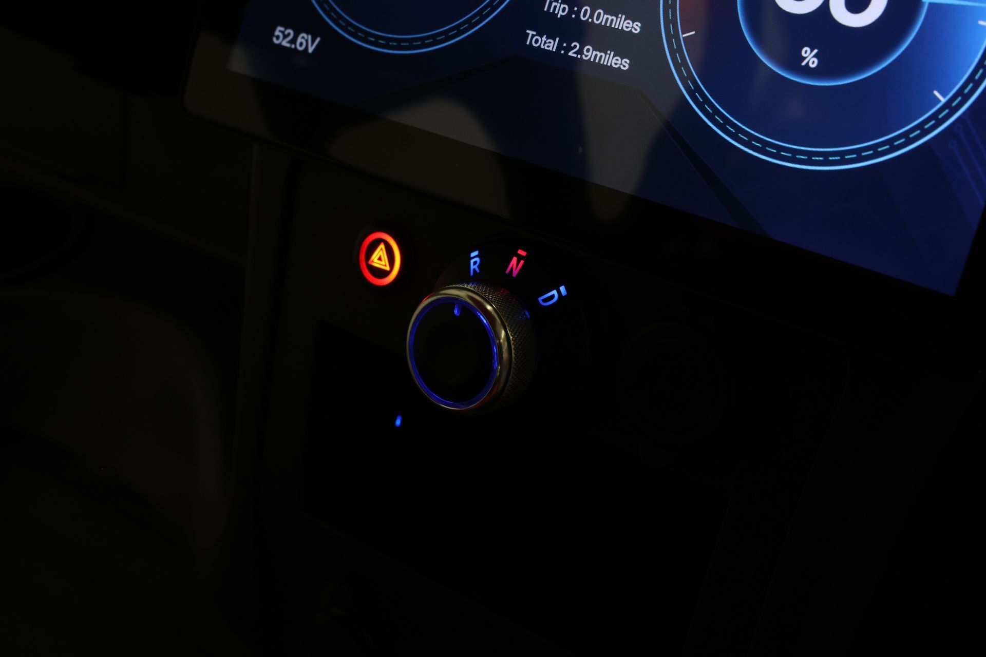 A close up of a car dashboard with a red light on it.