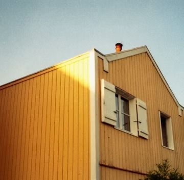 Yellow house exterior with white shutters under a blue sky
