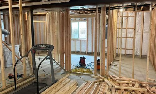 Framed interior under construction with exposed studs, a ladder, and tools on the floor.