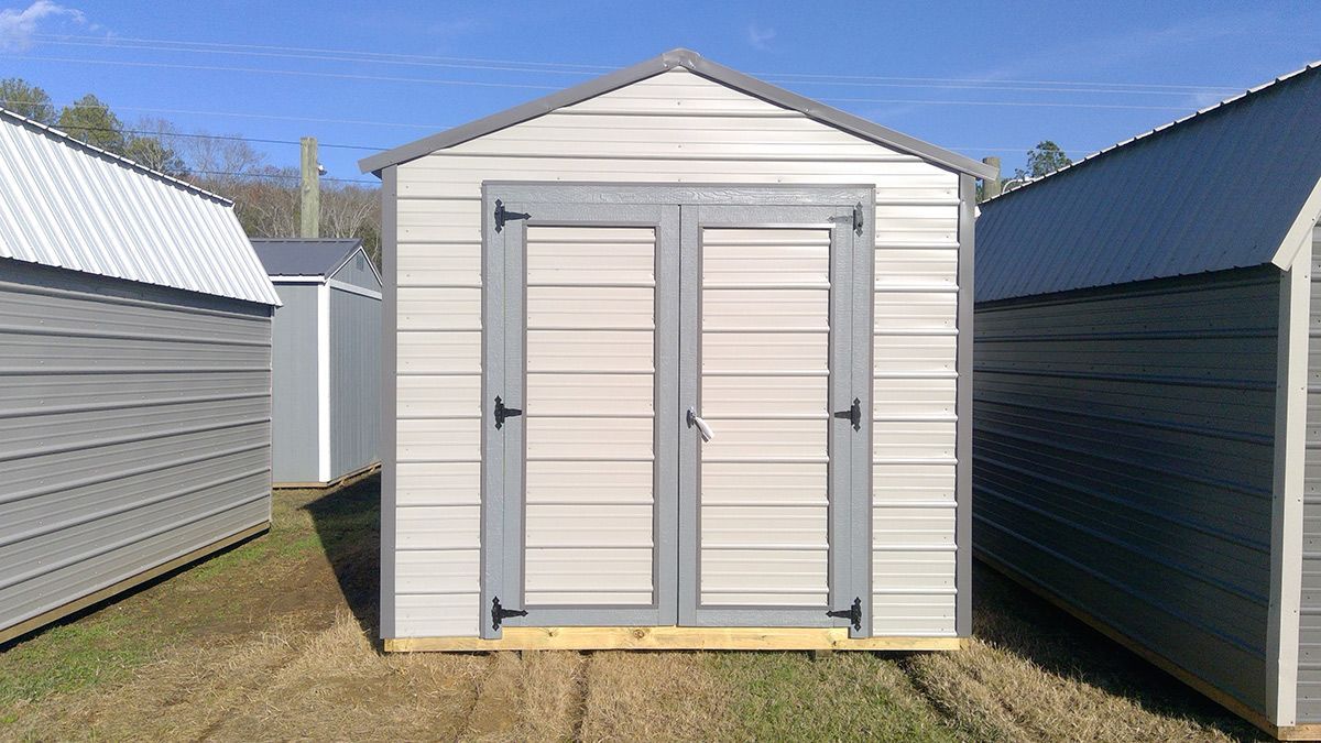 A row of sheds are lined up in a field.